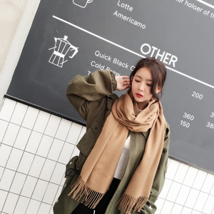 Close-up of soft khaki fringe scarf worn with olive green star pattern jacket in a cafe