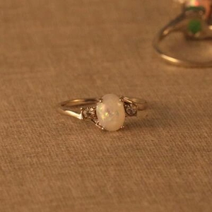 Nahaufnahme eines Silberrings mit ovalem Opal und kleinen Diamanten an der Seite
