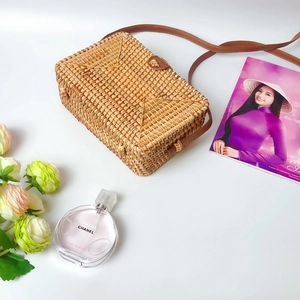 Rectangular woven rattan crossbody bag with brown leather strap and buckle detail