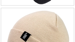 Close-up of beige ribbed knit beanie featuring the TRUE black textile logo label