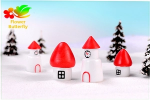 Miniature red house and clock tower figurines set on faux snow for winter decor