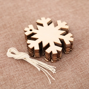 Set of snowflake wooden Christmas ornaments with cotton string on rustic burlap background