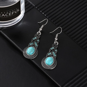 Détail de boucles d'oreilles bohèmes avec turquoise, strass bleus et finition argent rétro