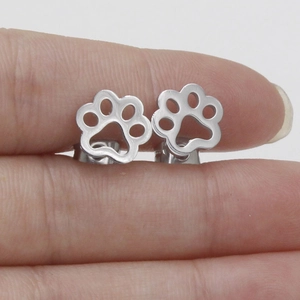 Macro shot of polished stainless steel dog paw print stud earrings held by hand