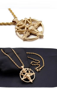Detailed macro shot of golden skull pendant on black leather and stone surface