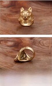 Detailed relief of golden wolf head stainless steel ring on a vintage wooden base
