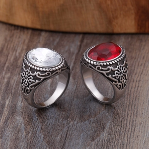 Bagues vintage homme en acier titane avec pierres rouges et blanches sur fond bois