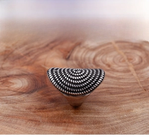 Detailed top view of retro silver punk ring with circular dot texture on wood background