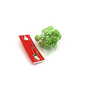 Close-up of 12 mini green mushroom ornaments with white dots in clear festive packaging