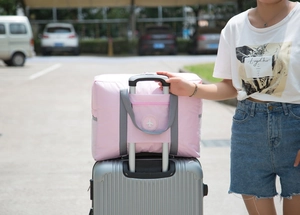 Pink travel bag mounted on a suitcase trolley handle showing the rear sleeve functionality