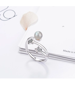 Detail view of silver star ring with moonstone and sparkling zircons on white paper