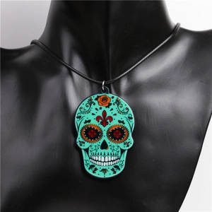 Close-up of green Day of the Dead candy skull acrylic pendant on black rope necklace