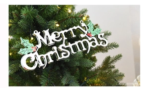 Silver Merry Christmas hanging ornament with holly leaves on a festive lit Christmas tree