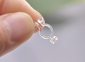 Macro view of transparent U-shaped resin ear clip converter with sparkling rhinestone