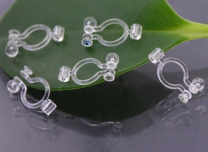 Macro shot of invisible clear U-shaped earring converters placed on a green leaf detail