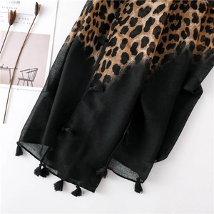 Detail of leopard print scarf with black tassel edges and elegant draped fabric texture