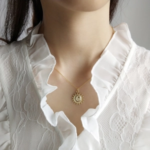 Close-up of a gold celestial pendant with sun and moon motifs on a female model