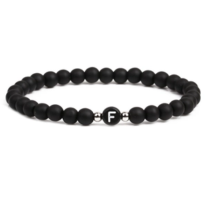 Detailed macro view of 6mm matte black stones and silver metal beads with letter F charm
