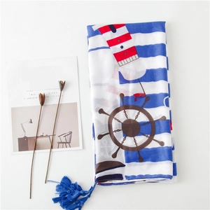 Gros plan d'un foulard en soie à rayures bleu-blanc avec motifs nautiques et pompons
