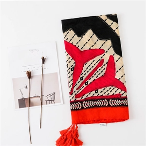 Détail montrant les franges rouges et la texture du foulard en coton à motifs