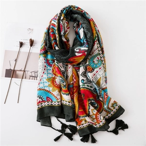 Détail du motif floral bohème sur une écharpe légère avec d'élégants pompons noirs