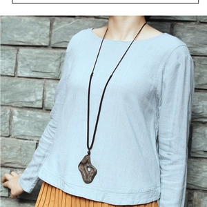 Ethnic style long sweater necklace featuring an irregular natural wooden pendant on model