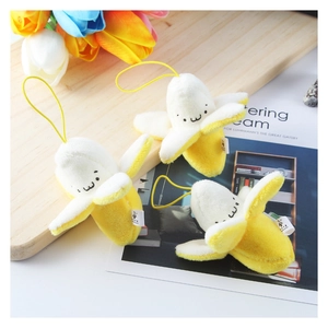Three cute peelable banana plush toys with emoticons and hanging straps on a flat lay