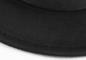 Detailed macro view of black wool felt texture and decorative ribbon trim on the hat