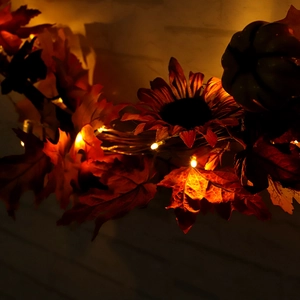 Autumn garland with maple leaves, sunflowers, black pumpkins, and warm LED light decoration