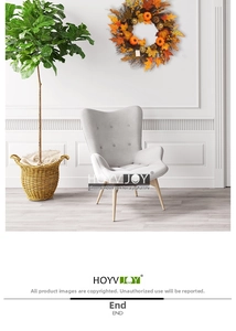 Fauteuil moderne en tissu gris clair avec une couronne d'automne de citrouilles et d'érables