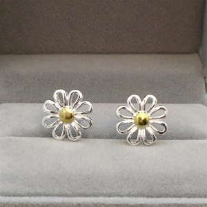 Detail of silver daisy stud earrings with golden centers on a gray velvet jewelry box