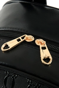 Detailed macro view of golden metal heart zippers on a black leather backpack