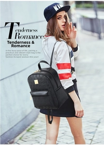 Detail of black faux leather backpack featuring gold logo plate and premium printed texture
