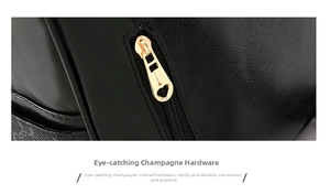 Detail of a champagne gold heart-shaped metal zipper pull on a black textured leather bag
