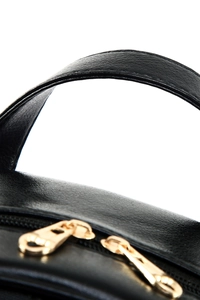 Close-up of black grainy leather texture and dual gold-tone metal zippers on the backpack