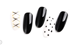 Close-up of black and white nail art tips featuring polka dots and golden lace patterns