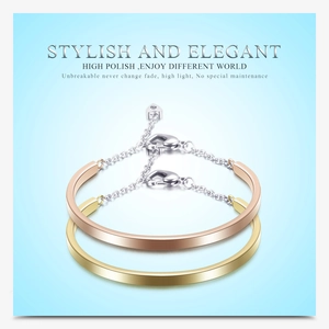 Polished U-shaped bangles in gold and rose gold with heart charms and lobster clasps