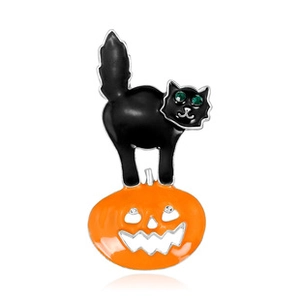 Close-up of a black enamel cat brooch with an orange pumpkin and green crystal eyes