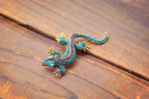 Macro detail of lizard brooch with colorful crystals on dark wooden background