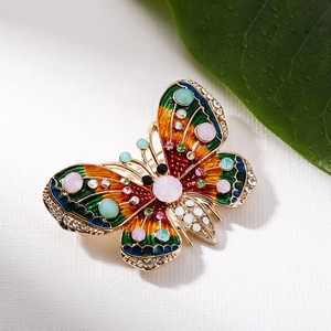 Close-up of colorful enamel butterfly brooch with inlaid rhinestones on a green leaf