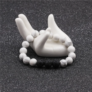Detail view of 10mm white turquoise and volcanic lava stone beads on hand display