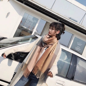 Outdoor model wearing a long soft plaid scarf with tassels in earth tones and cream colors