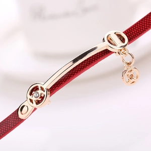Detail of red textured PU leather strap with golden charm and sparkling rhinestones