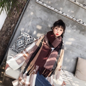 Detail of soft cashmere-feel scarf with long tassels and autumn plaid pattern