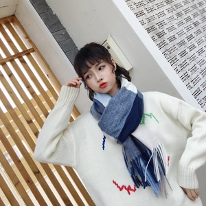 Detail of blue and grey plaid knit scarf with fringed edges on model outdoors