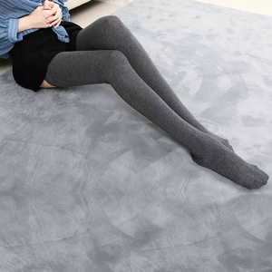 Detail of grey knitted over-the-knee socks showing soft texture on a plush rug