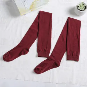 Detailed top view of wine red cotton thigh high socks laid on a white textured fabric