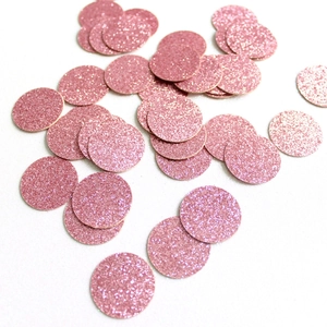 Macro shot of sparkling pink glitter round confetti scattered on a white surface