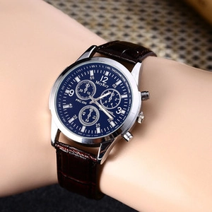 Close-up of a blue dial chronograph watch with a brown leather strap on a wrist