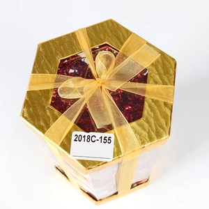 Christmas tree ornaments in a gold hexagonal gift box with a sparkling red festive ball